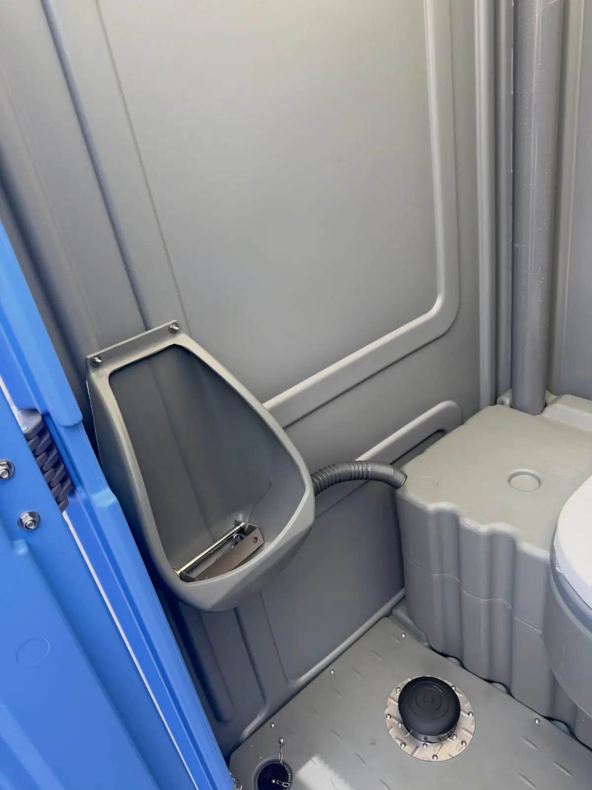 Inside a serviced porta potty showing the urinal and clean floor