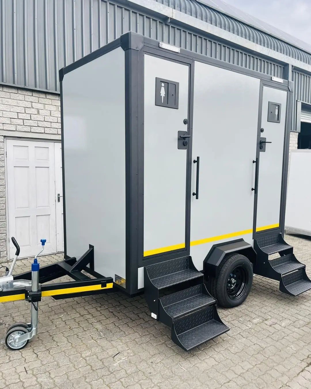 Exterior of a two-stall restroom trailer with men and women signs and fold-down steps